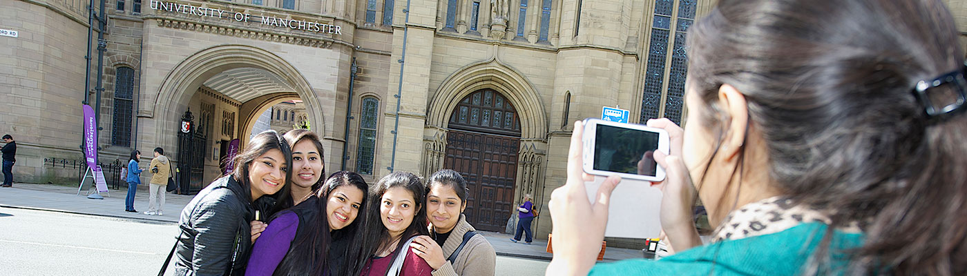 female student taking a photo of her friends outside The University of Manchester